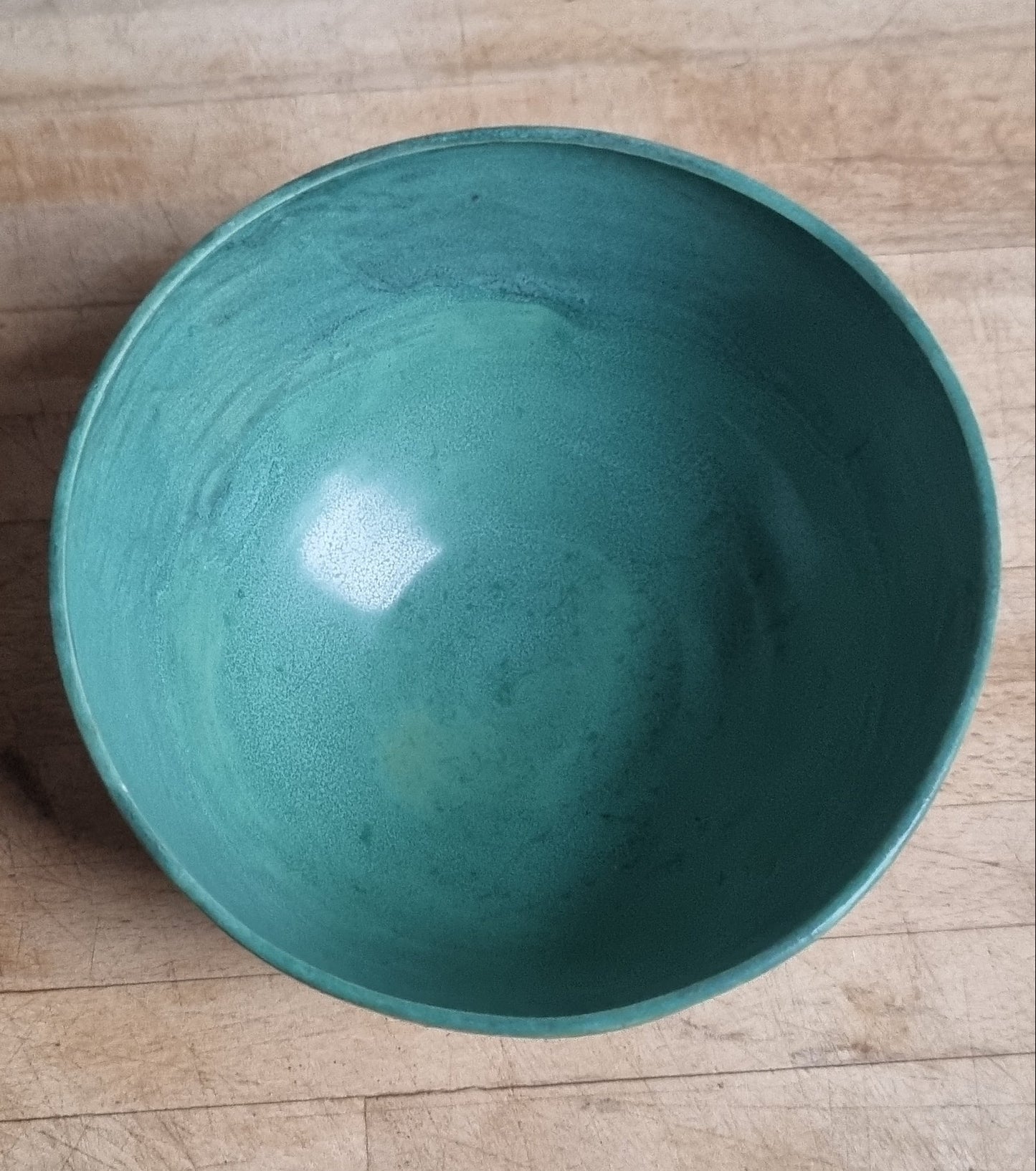Teal ceramic bowl on a wooden surface