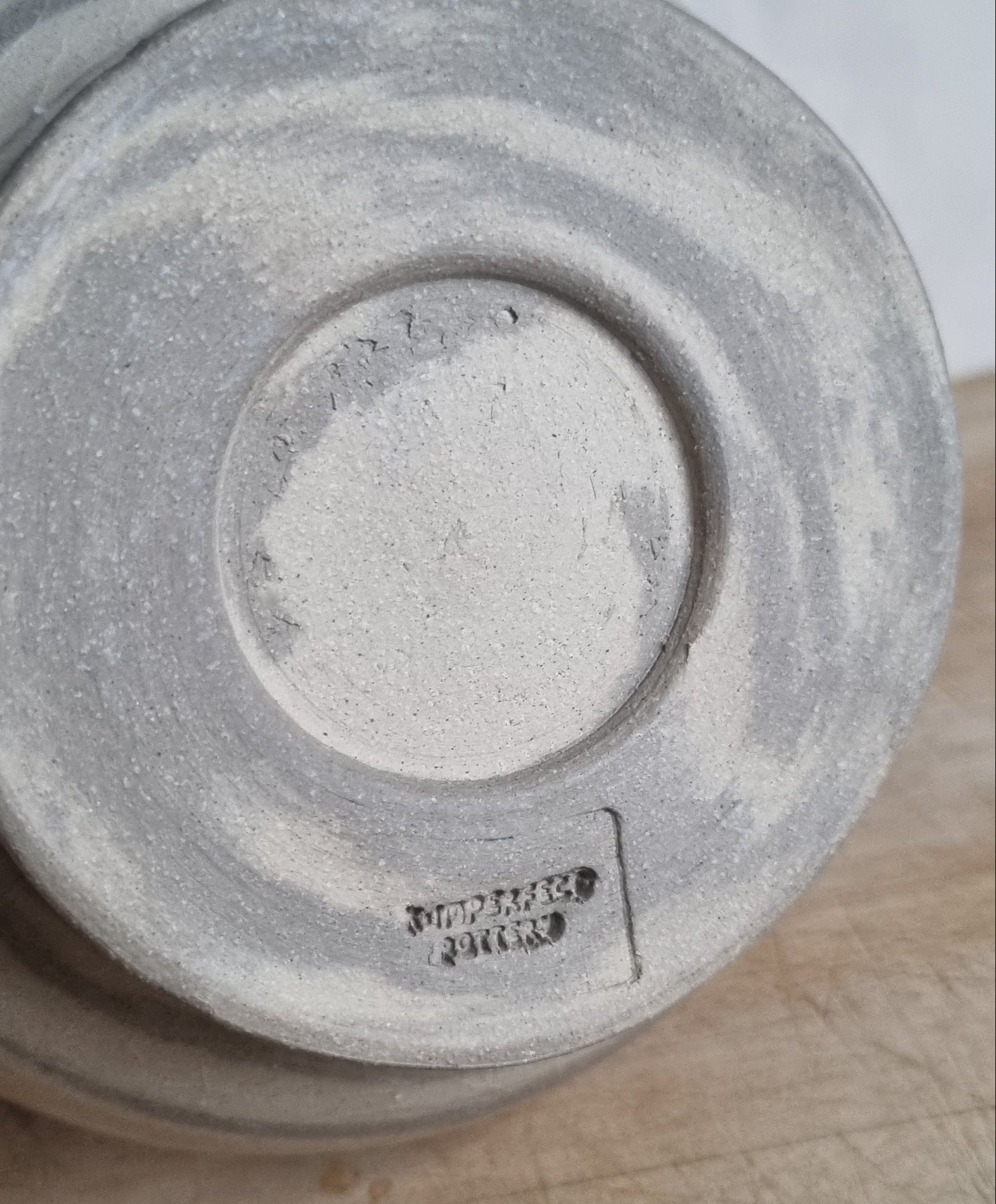 Gray ceramic bowl base showing stamped logo on a wooden surface